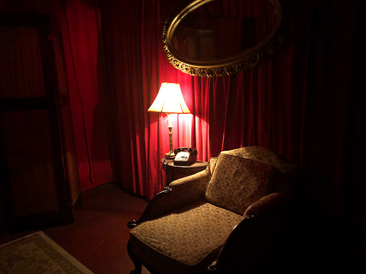 A dimly lit hallway with an old phone and chair