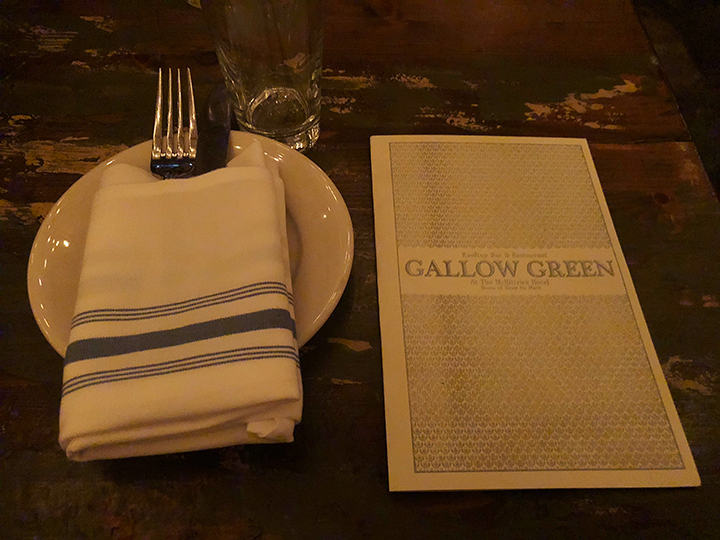 Wooden table and Sleep No More ad inside the menu