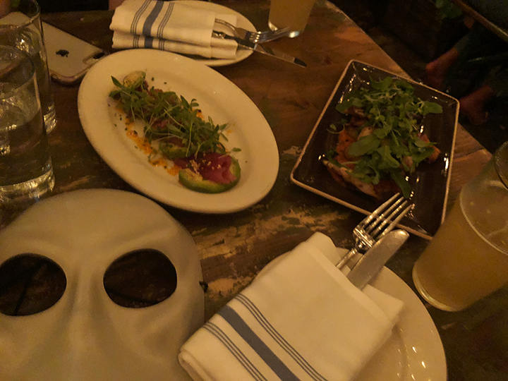 Sleep No More mask on the table next to drinks and dishes