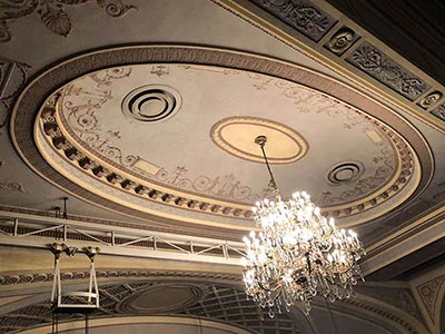 A grand chandelier illuminating the theatre interior, with an Adam-style ceiling